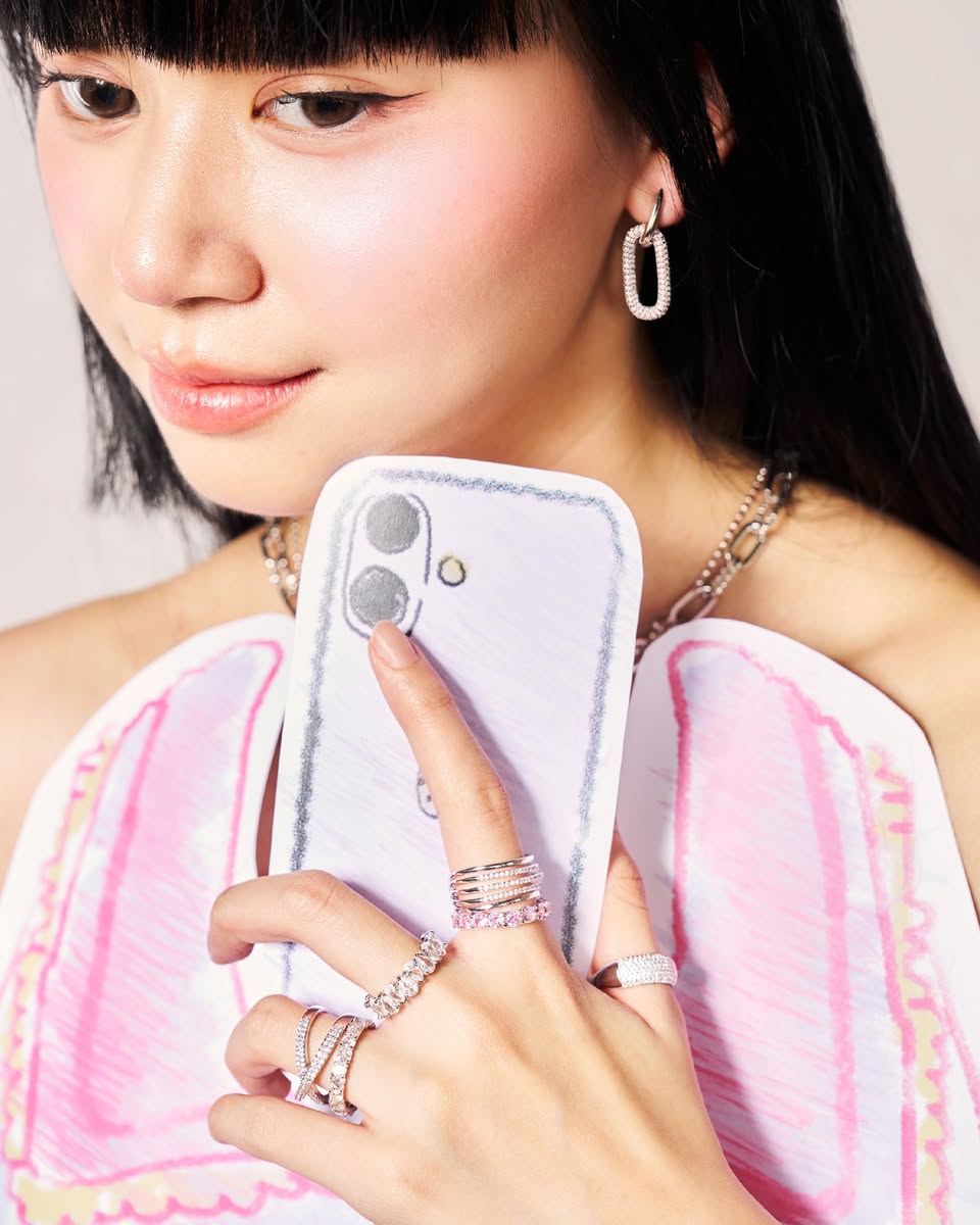 Close-up of silver hoop earring, layered rings, and chain necklace