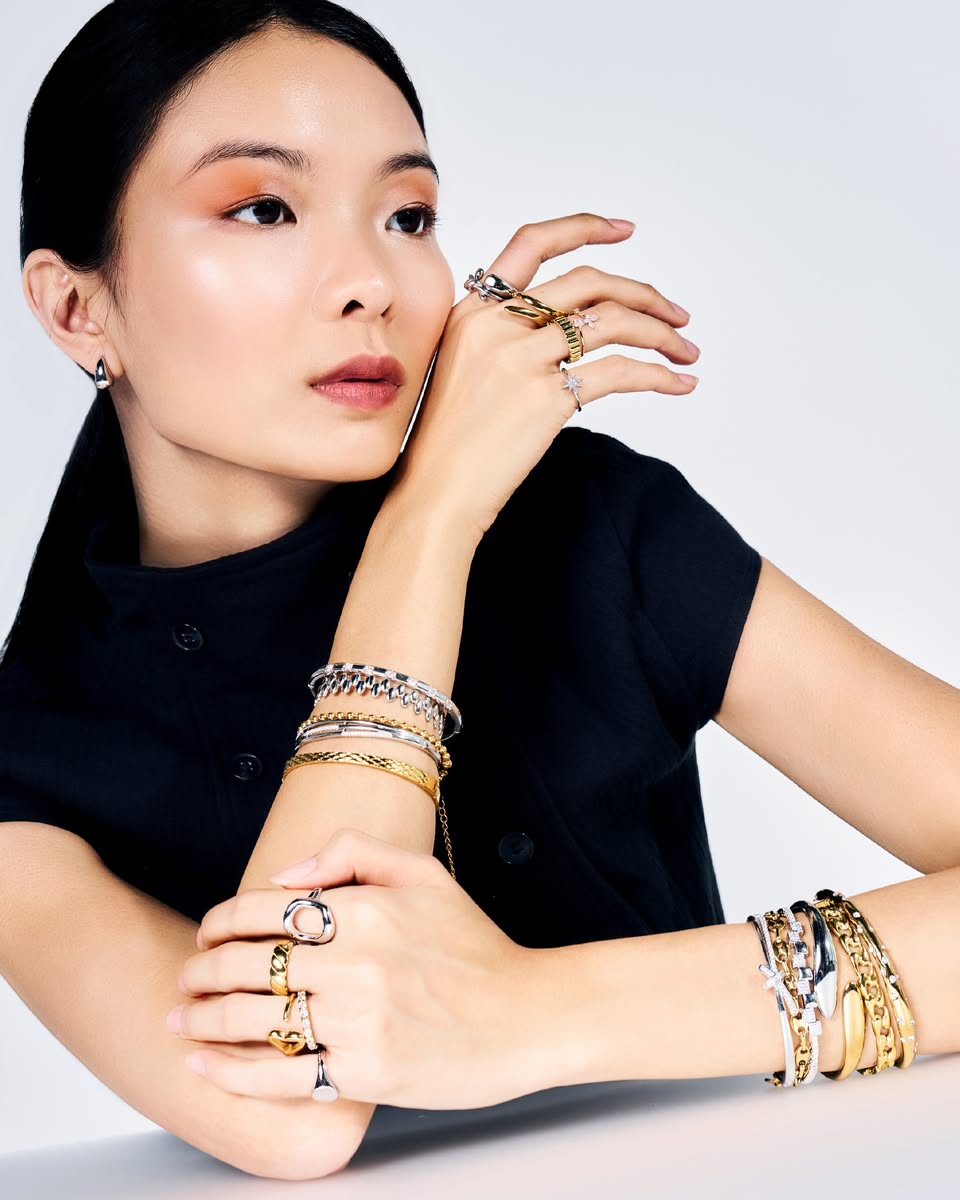 Model wearing stacked rings and gold chain bangles from Kaleido Jewellery