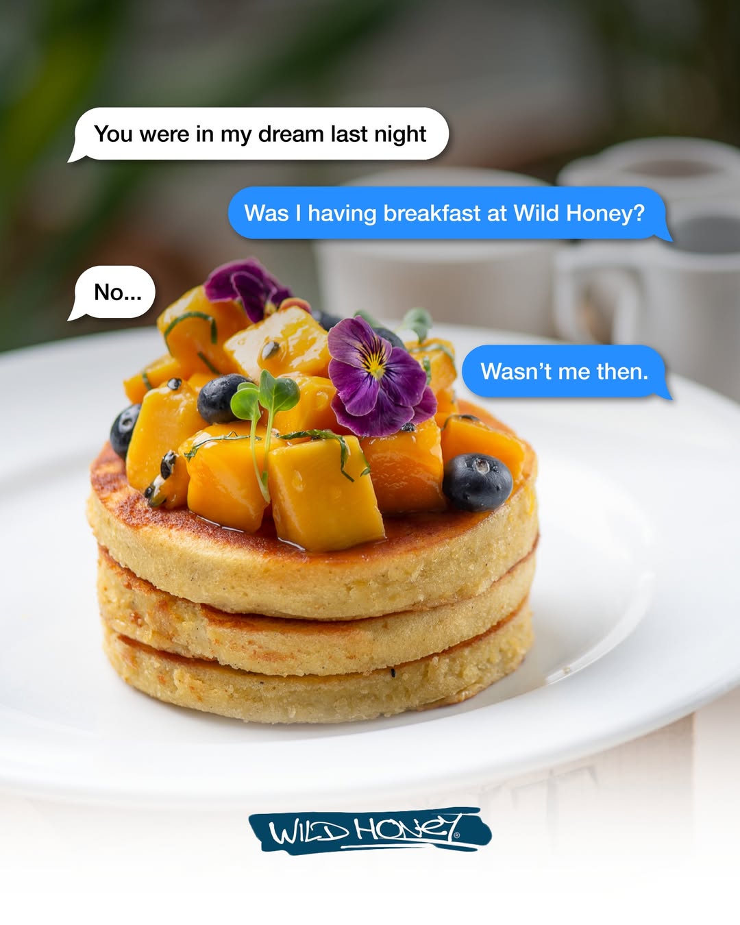 Wild Honey pancakes with mango, blueberries, and edible flowers