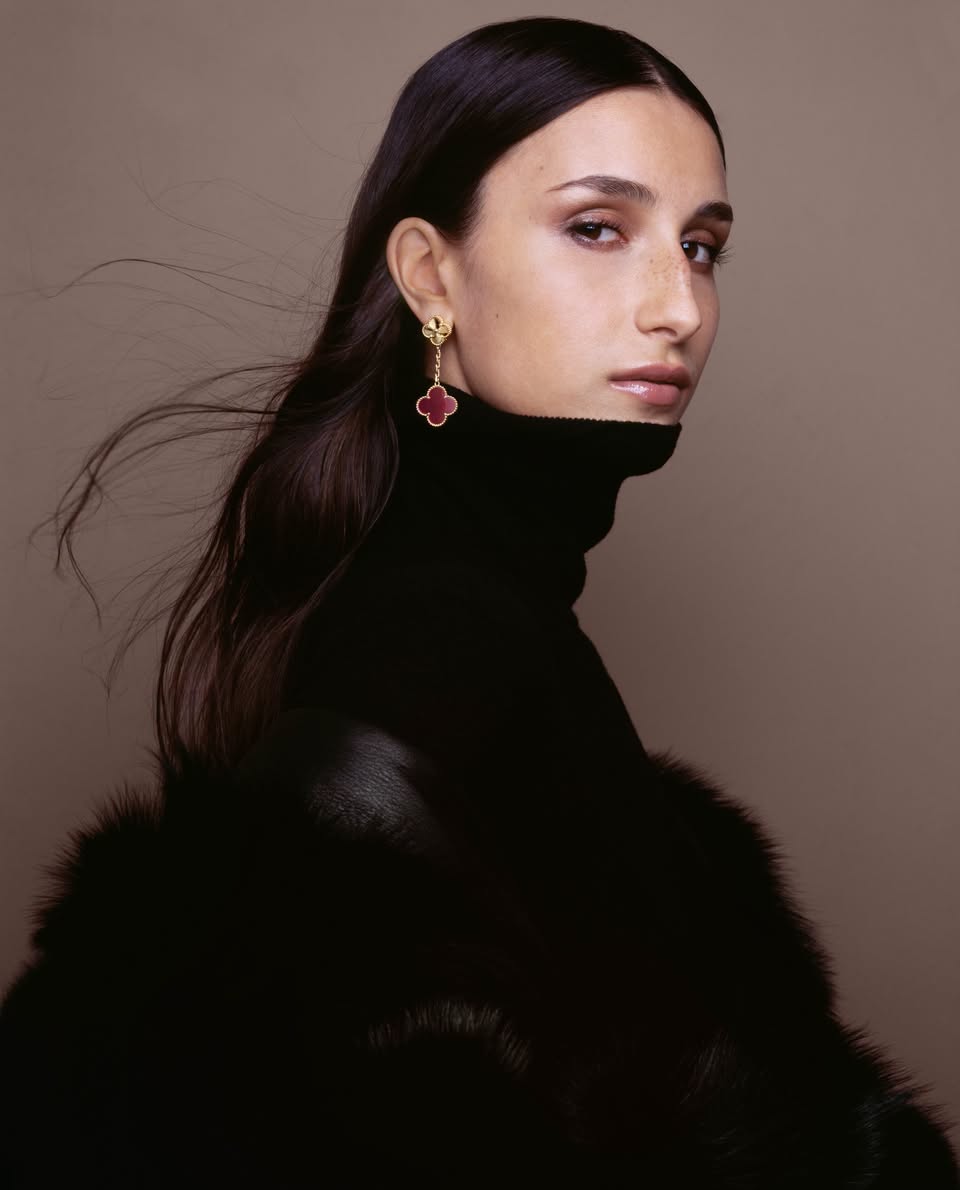 Van Cleef & Arpels pink Alhambra earrings styled with a black turtleneck and fur coat