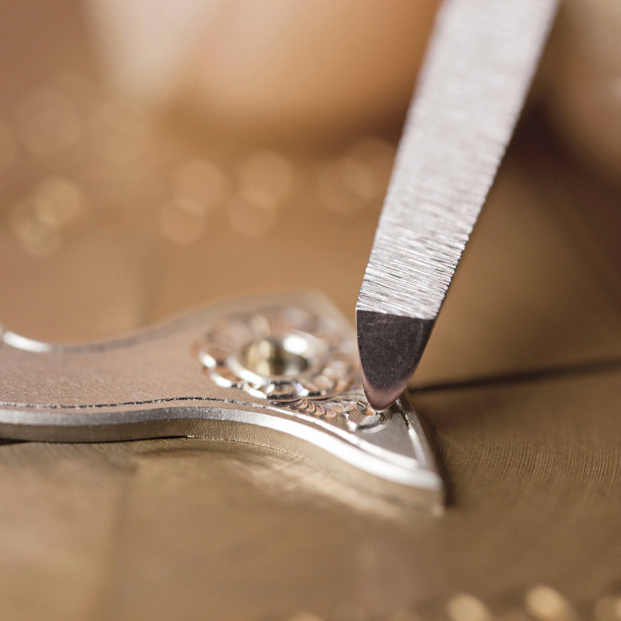 Engraving tool working on an ornate silver component