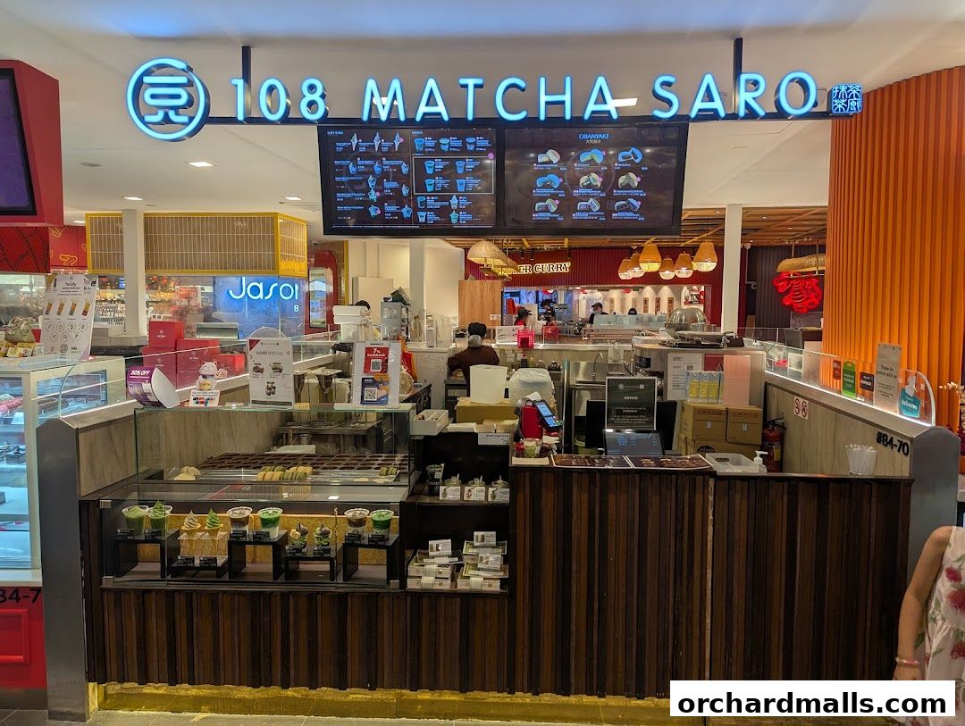 A brightly lit matcha dessert shop with a prominent neon sign and display cases filled with treats.