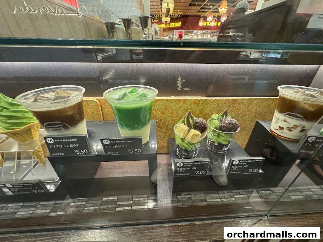 A display case showcasing various matcha and hojicha drinks and desserts from 108 Matcha Saro.