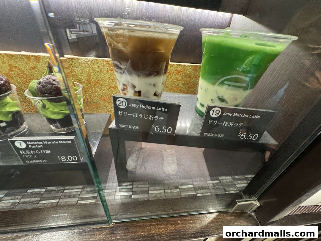 A display case featuring three matcha and hojicha desserts and drinks.
