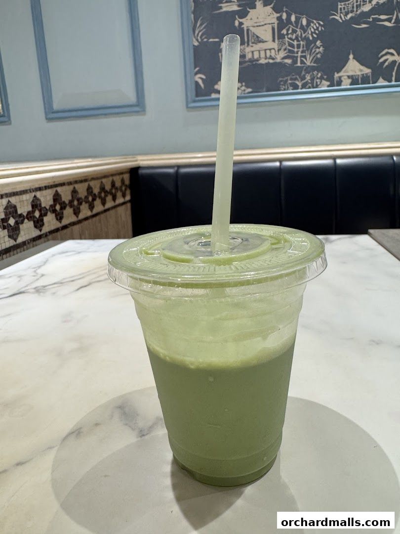 A refreshing green matcha drink in a clear plastic cup with a straw.