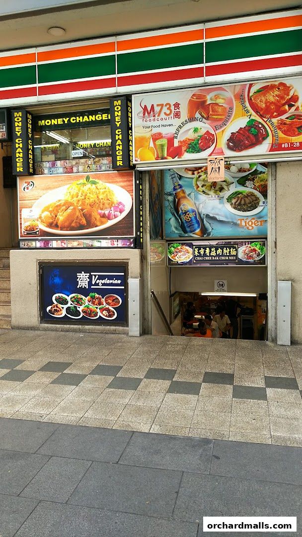 7-Eleven shop front with money changer and food advertisements, including a food court.