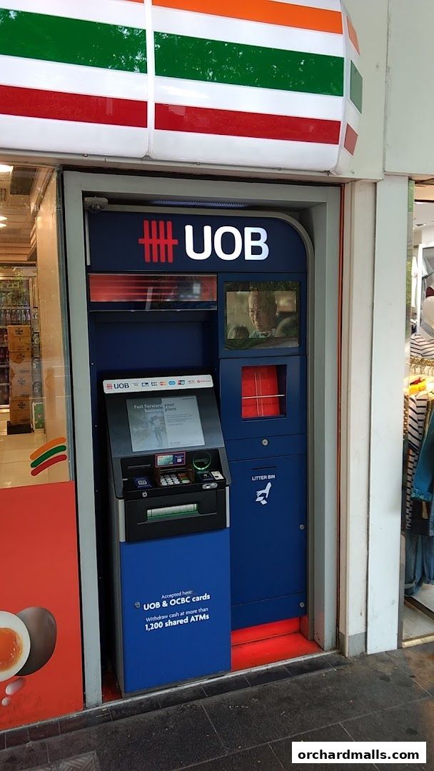 A 7-Eleven store entrance with a UOB ATM machine and advertising.