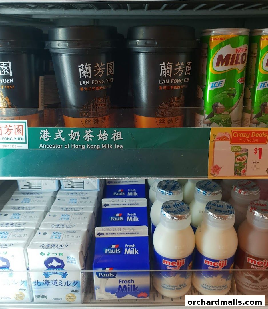 A refrigerated display case filled with various milk drinks and canned beverages.
