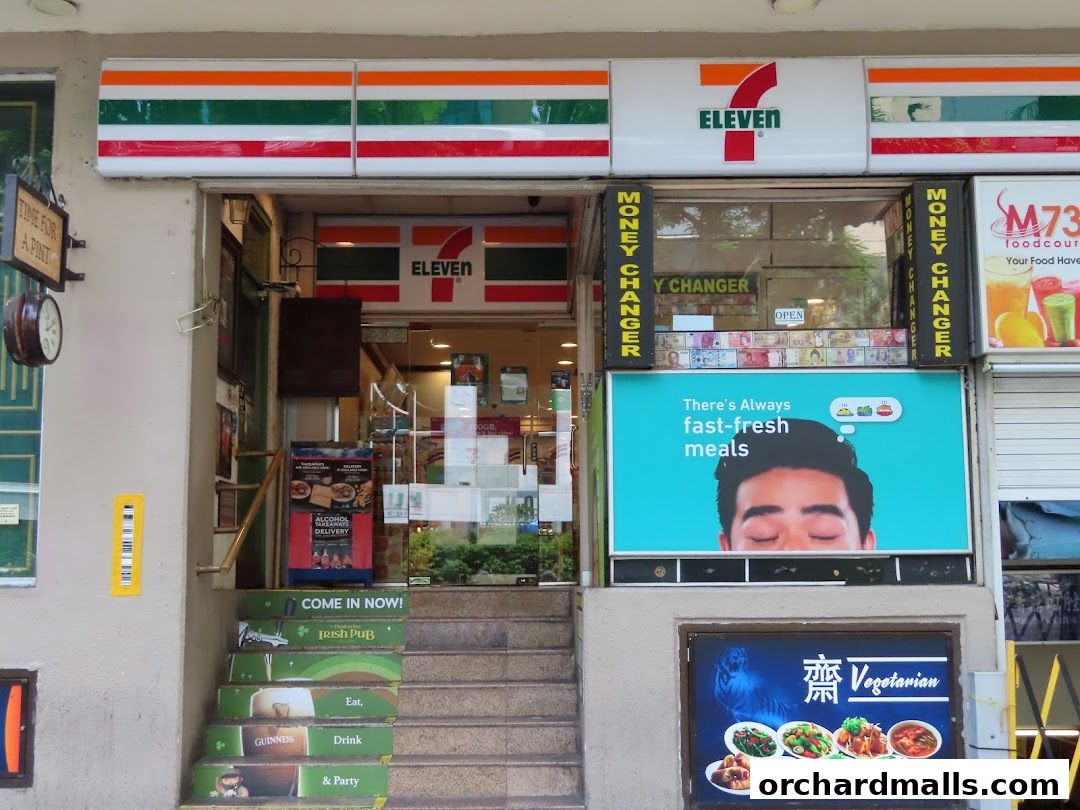 The entrance of a 7-Eleven convenience store with promotional signs and a money changer.