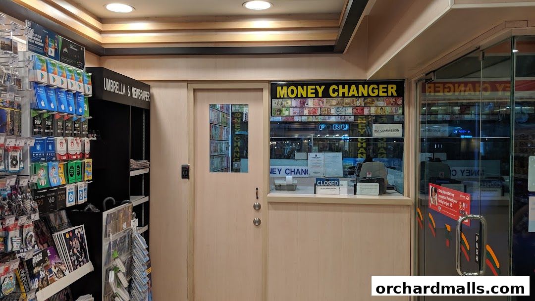 Interior view of a 7-Eleven store with a money changer counter and retail displays.