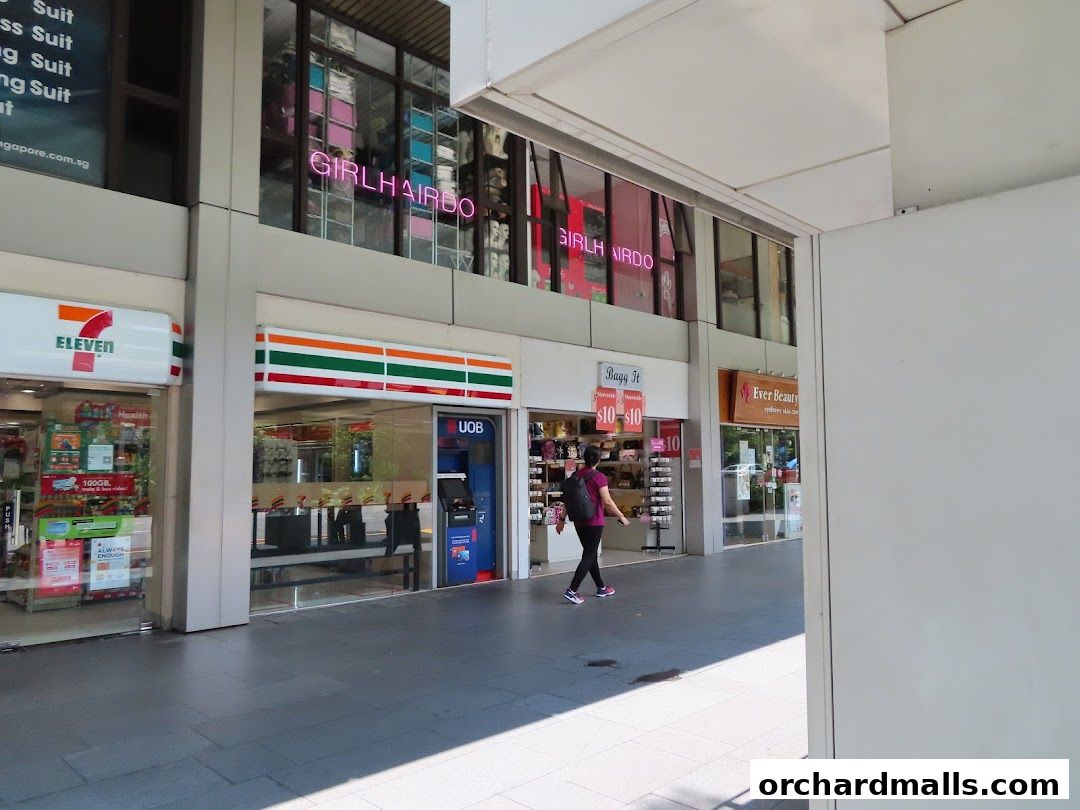 Exterior view of a 7-Eleven convenience store and other shops on a sunny day.