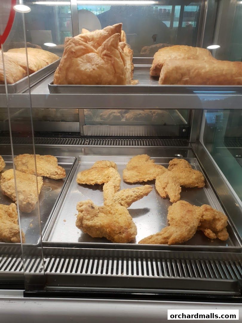 A display case filled with golden fried chicken wings and pastries.