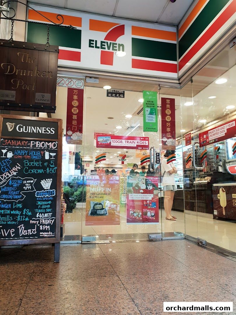The entrance of a 7-Eleven convenience store with promotional posters and a Guinness chalkboard menu.