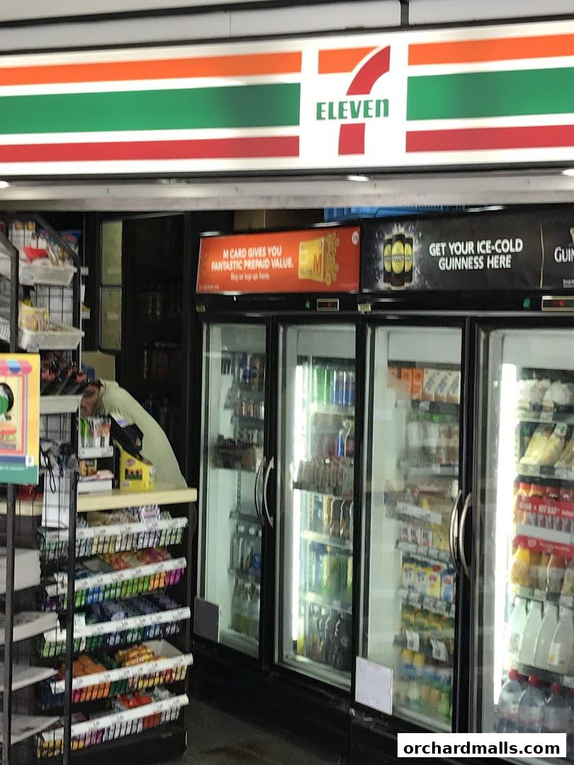 A 7-Eleven convenience store interior with refrigerated drinks and snacks displayed.