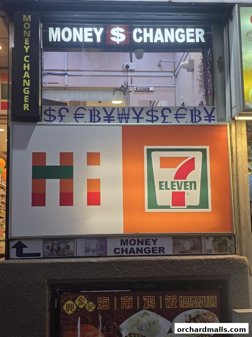 A 7-Eleven store with a prominent "Money Changer" sign and currency symbols.