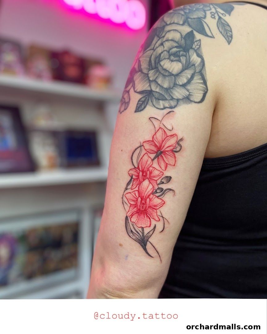 A person's arm displays a vibrant red orchid tattoo with a grey rose tattoo on the shoulder.