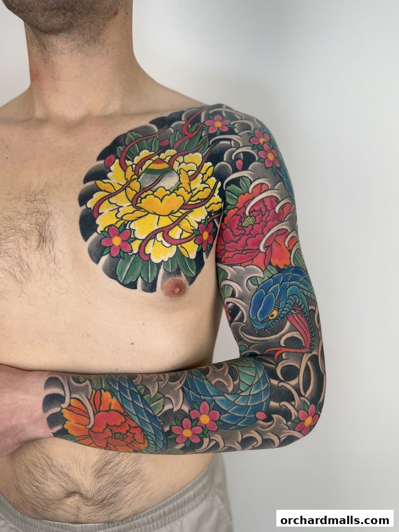 A person displays a vibrant, full-sleeve tattoo featuring peonies, cherry blossoms, and a snake.