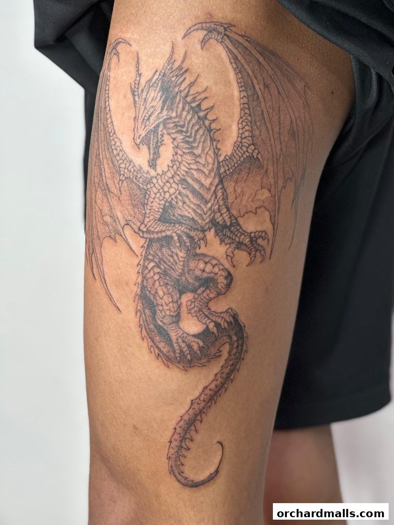 A detailed black and grey tattoo of a dragon on a person's thigh.