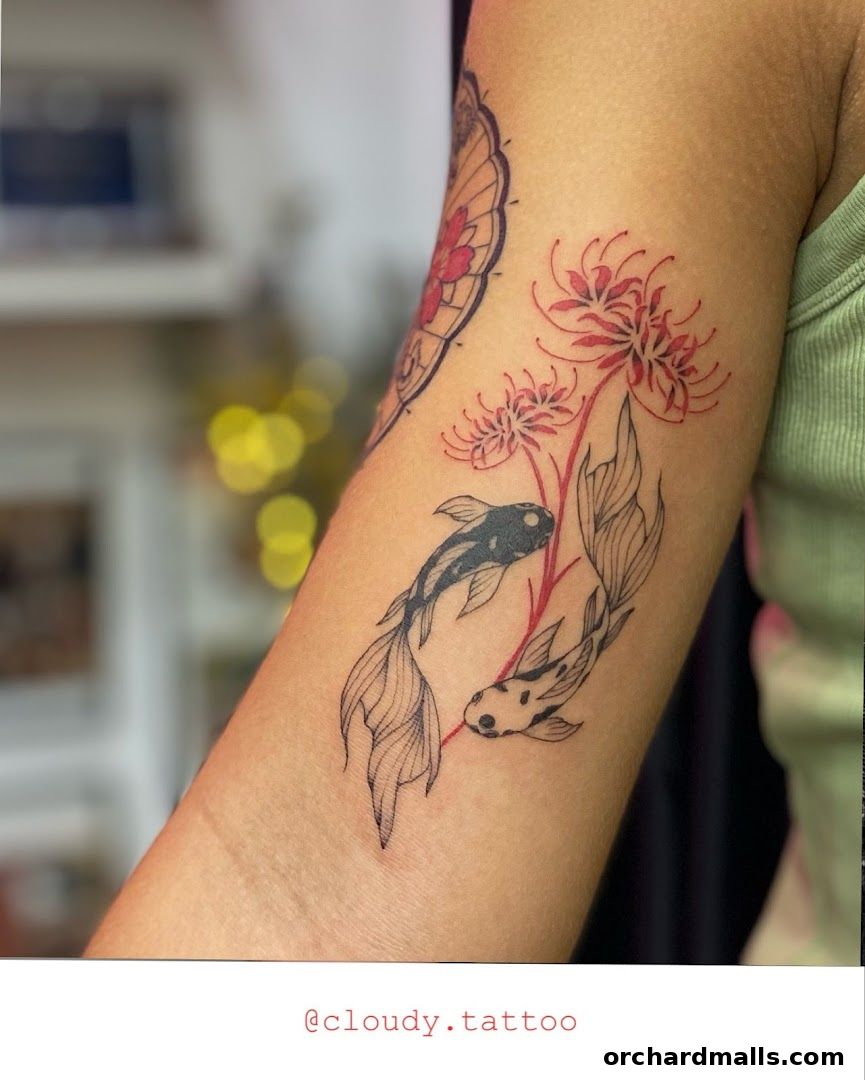 A close-up of a tattoo featuring koi fish and spider lilies on an arm.