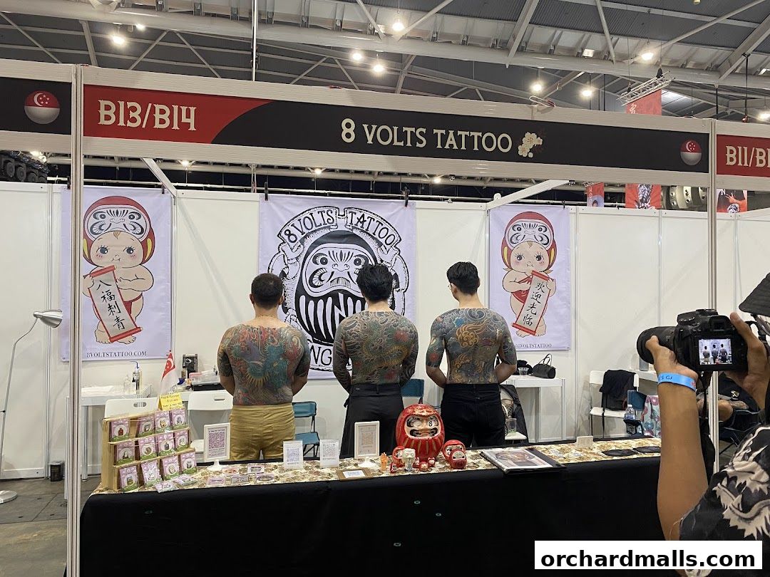 Tattoo artists display their intricate back tattoos at the 8 Volts Tattoo booth.