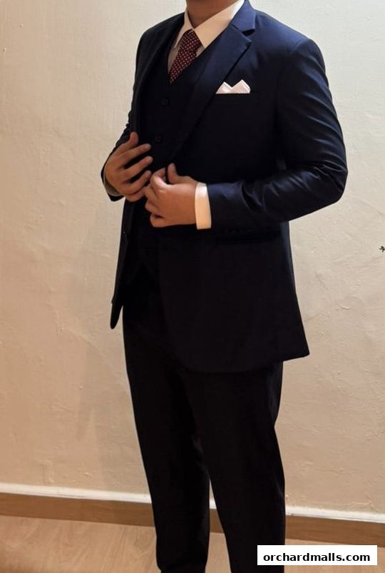 A person wearing a navy blue three-piece suit with a white pocket square and a patterned tie.