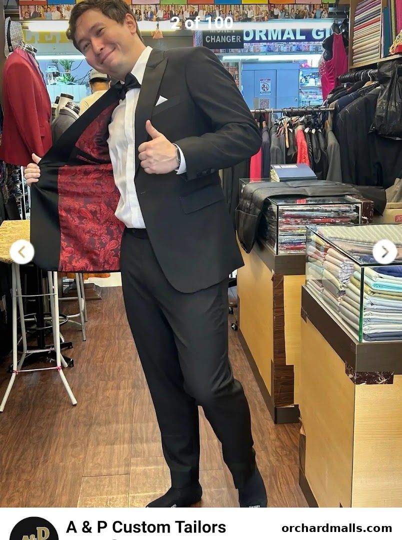 Man in a custom-tailored black suit with a patterned lining, showing off his attire.