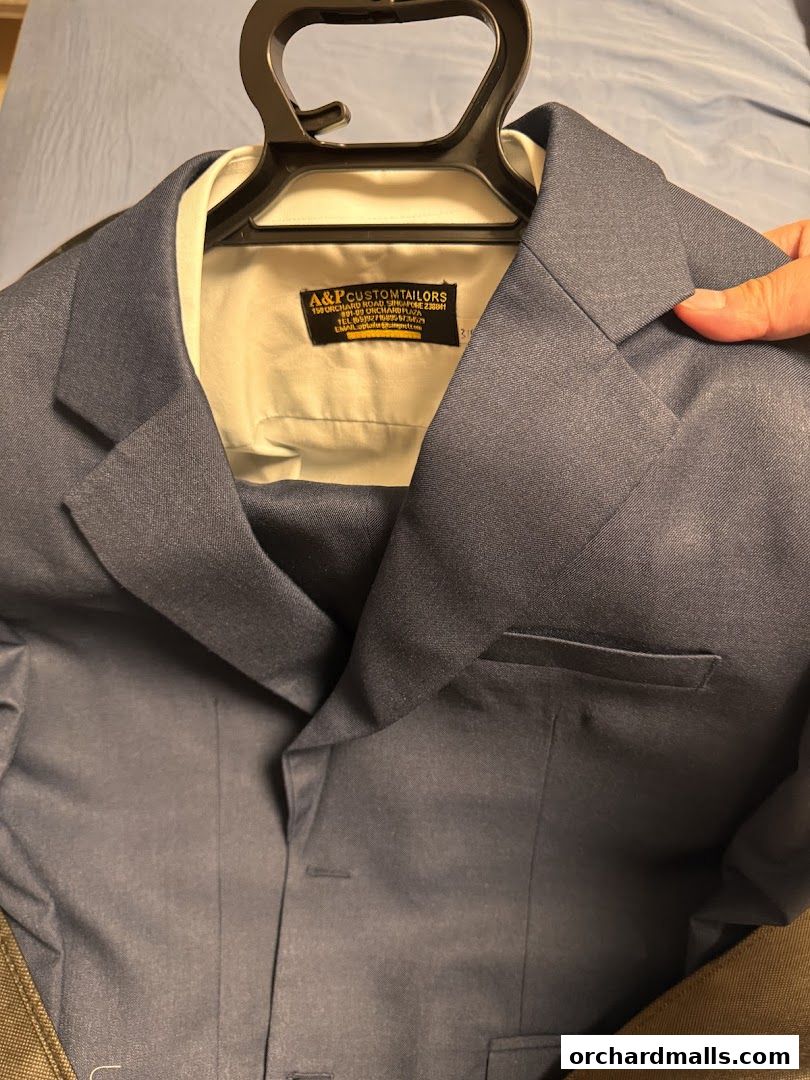 A close-up of a blue custom-tailored suit jacket with a label from A&P Custom Tailors.