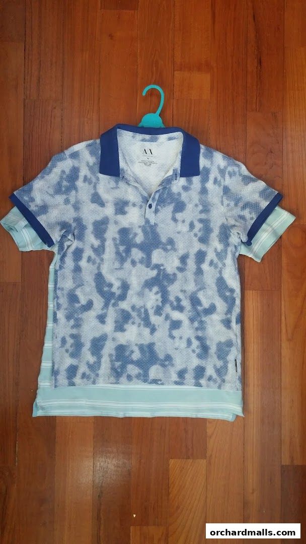 A blue and white patterned polo shirt from AX Armani Exchange hangs on a hanger.