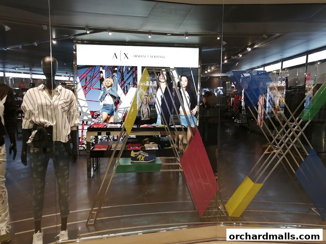 Mannequins display fashion clothing in a modern AX Armani Exchange store window.