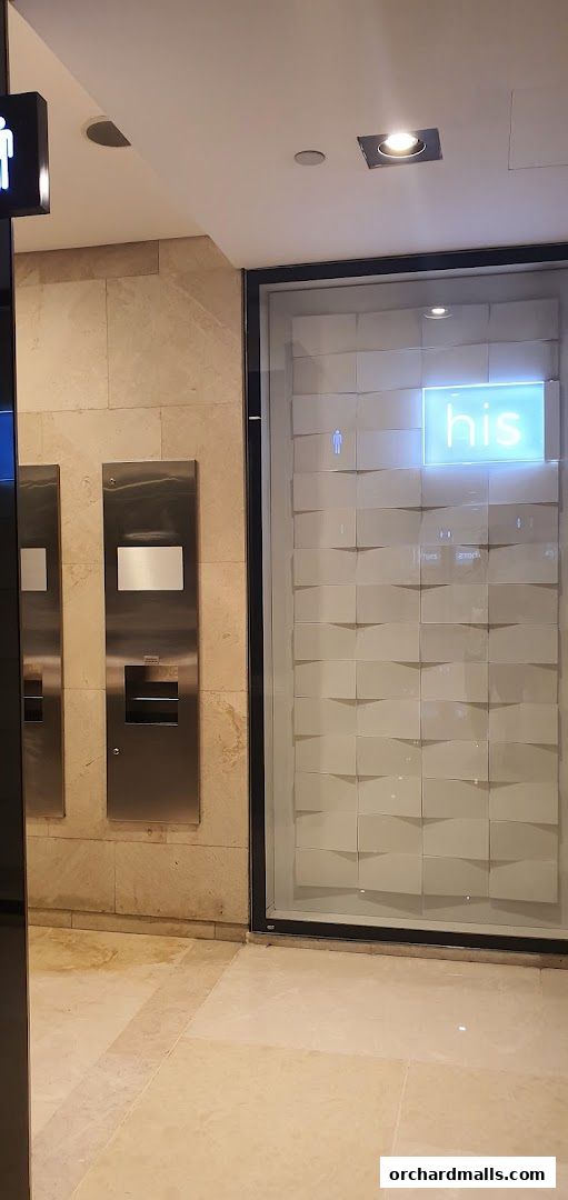 A modern restroom entrance with a glowing 'his' sign and a textured wall.