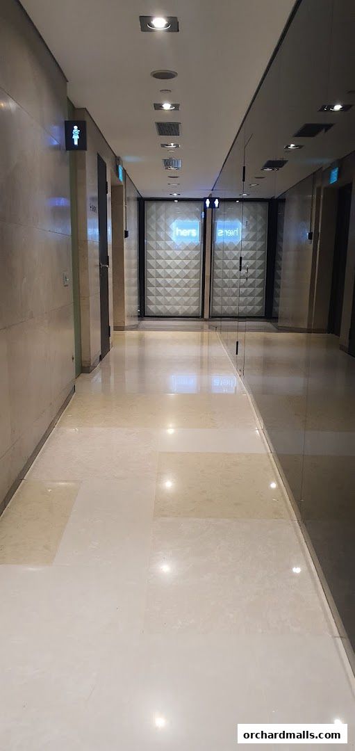A modern hallway with polished floors and illuminated signs for restrooms.