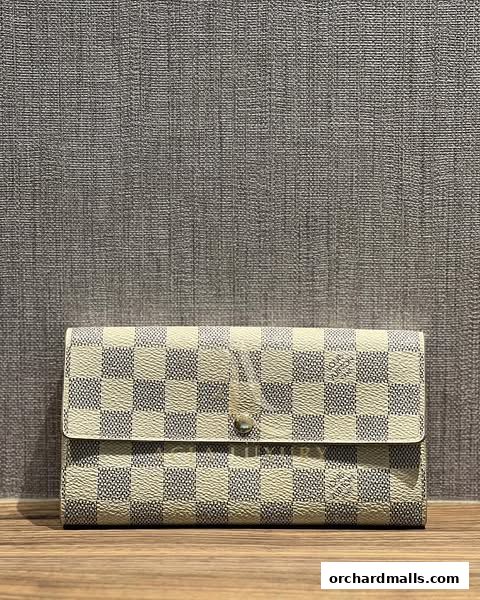 A close-up shot of a checkered luxury wallet with a button closure.
