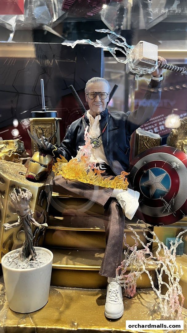 A detailed action figure of Stan Lee in a heroic pose with Marvel memorabilia.