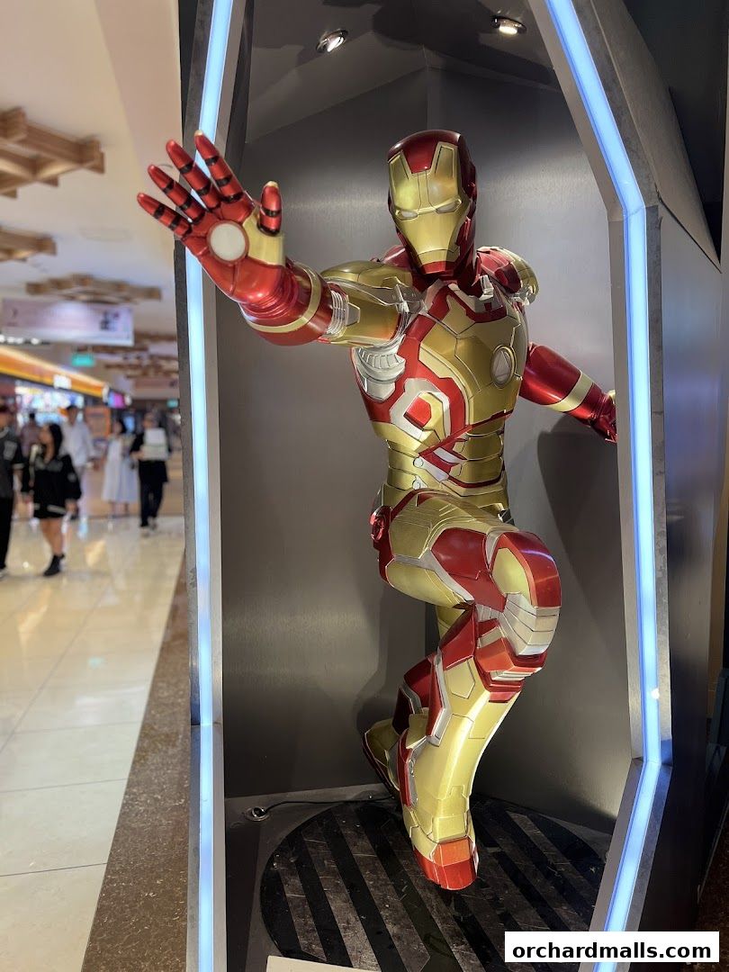 A life-sized Iron Man statue is displayed in a modern, illuminated booth.