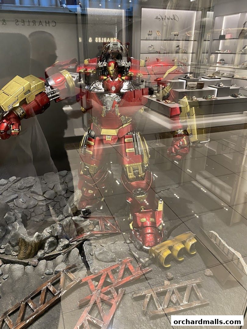 A large Hulkbuster Iron Man figure displayed in a shop window with a shoe store in the background.