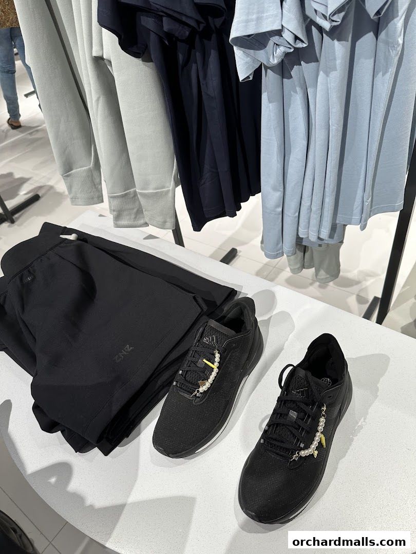 Adidas performance wear including black shorts, black sneakers with pearl accents, and various t-shirts on display.