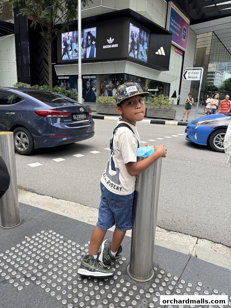 A young boy stands on a sidewalk in front of the Adidas Performance Store.