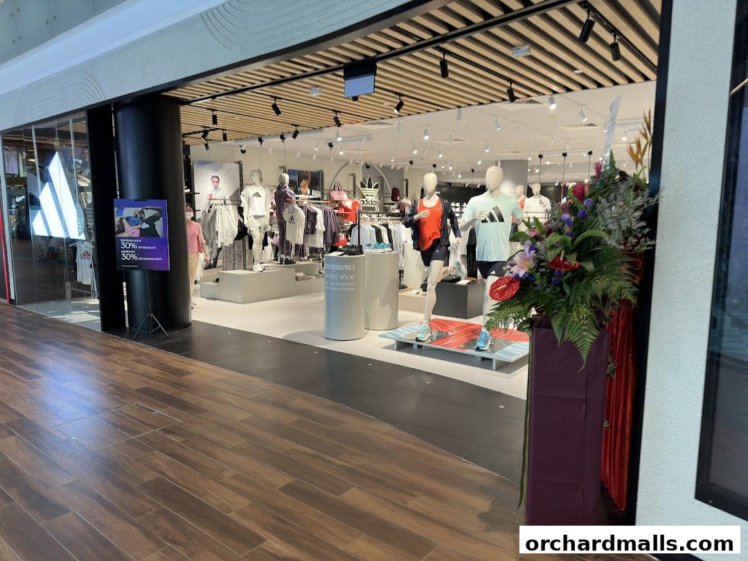 The entrance of an Adidas Performance Store with mannequins displaying athletic wear and a promotional sign.