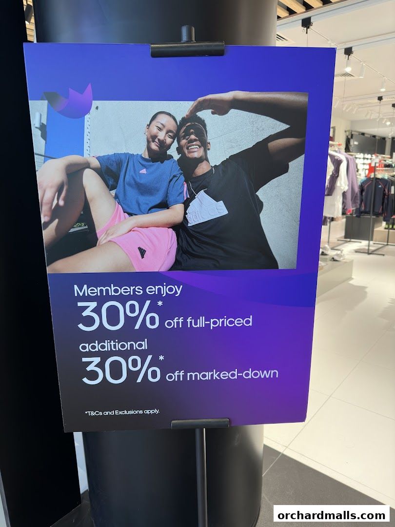 A sign advertising 30% off for members at Adidas, with a picture of two people.