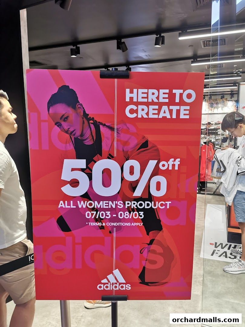 A sign advertises 50% off all women's products at Adidas.
