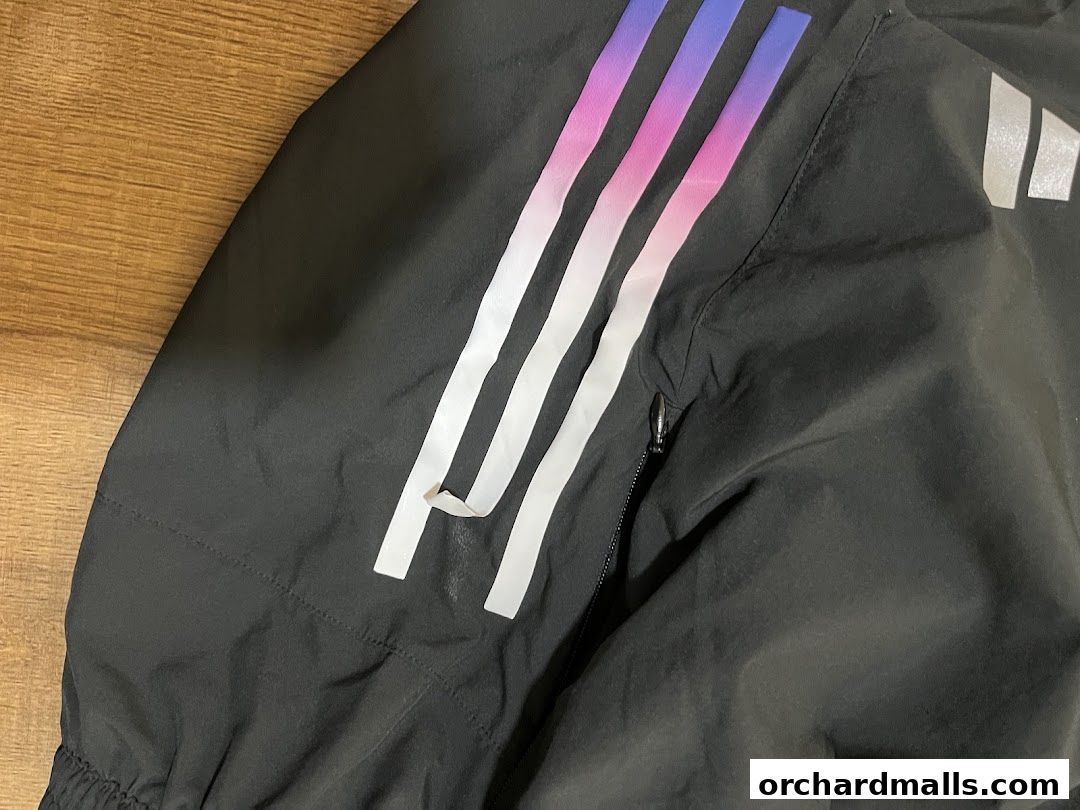 Close-up of a black Adidas jacket with gradient stripes and the iconic three stripes.