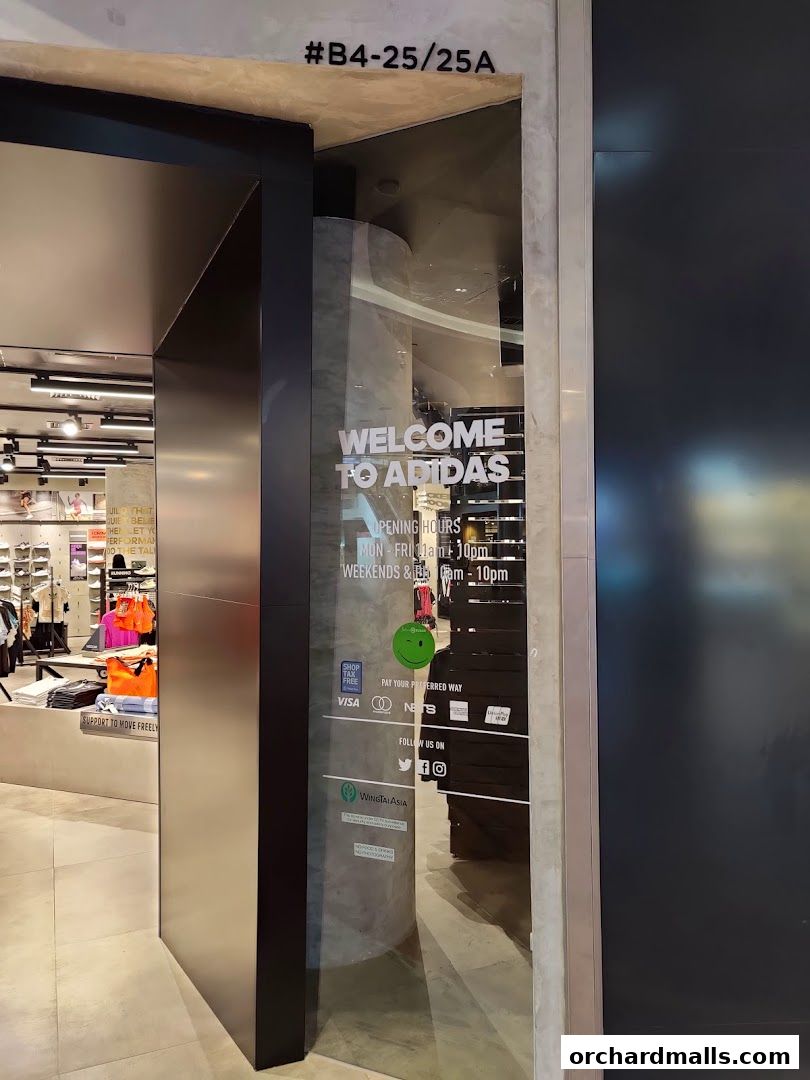 The entrance to an Adidas Performance Store with opening hours and payment options displayed on the glass.