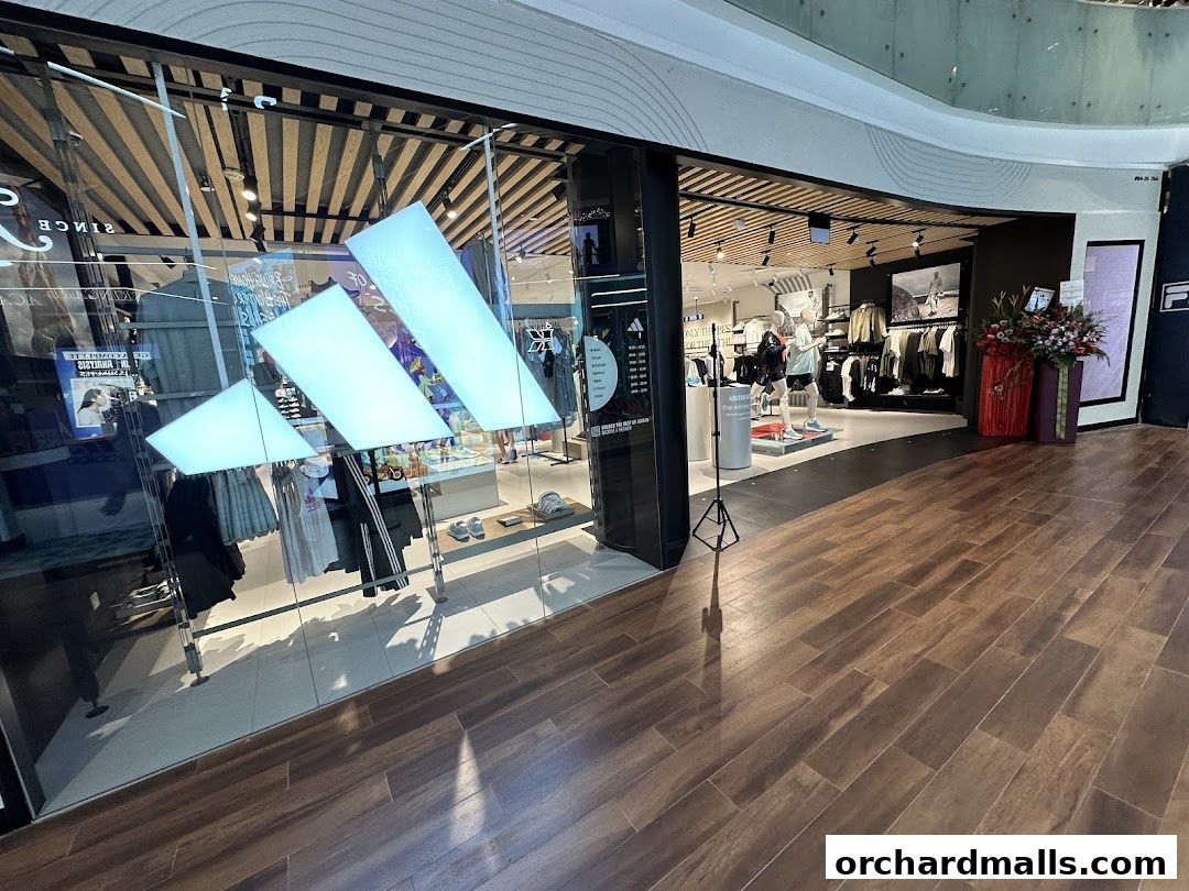 The entrance of an Adidas Performance Store with its iconic logo and displays of athletic wear.