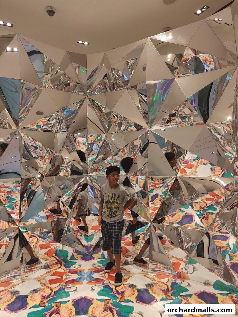 A young boy stands in a room with mirrored walls and a colorful, patterned floor.
