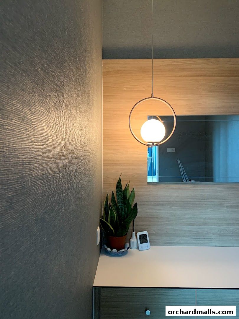 A modern interior corner with textured walls, wood paneling, a hanging lamp, and a snake plant.