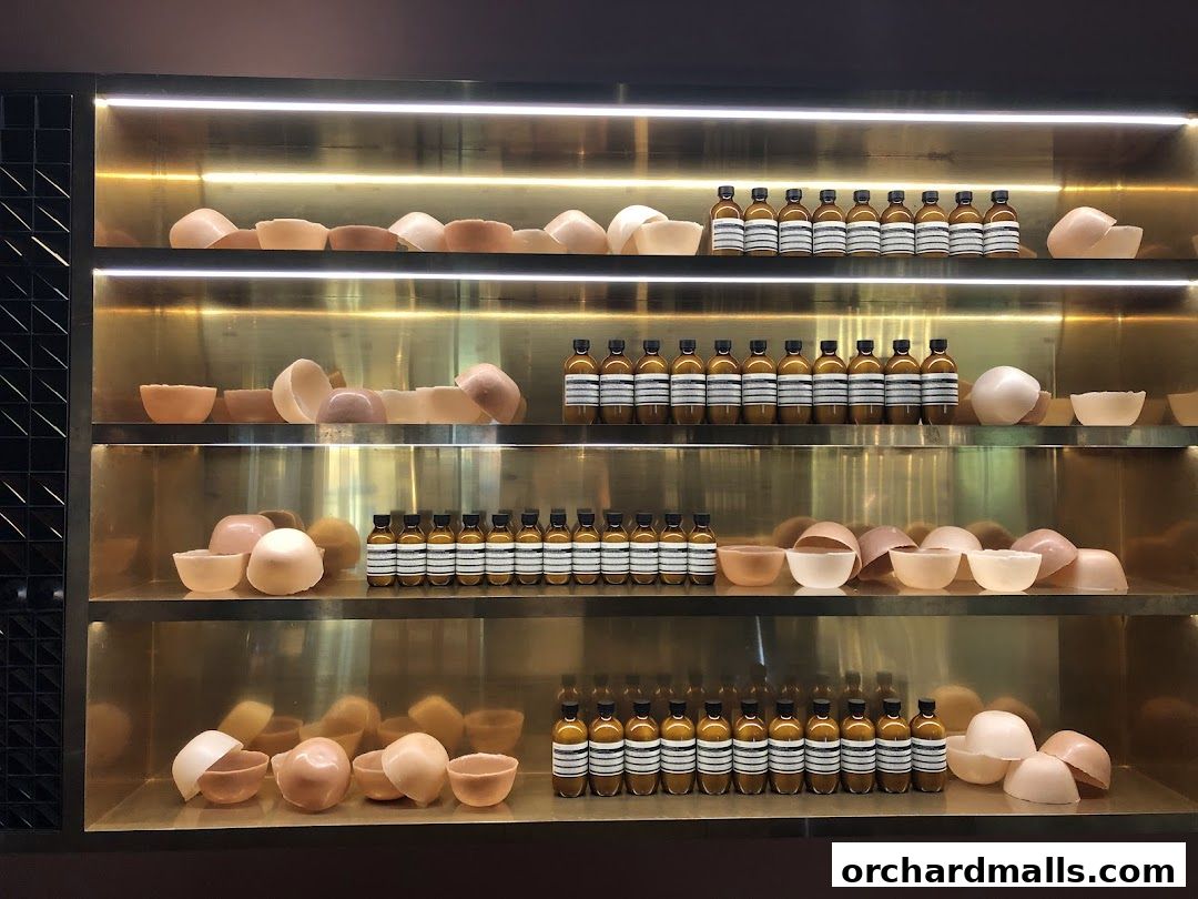 Shelves displaying Aesop products, including bottles and bowls, with warm lighting.