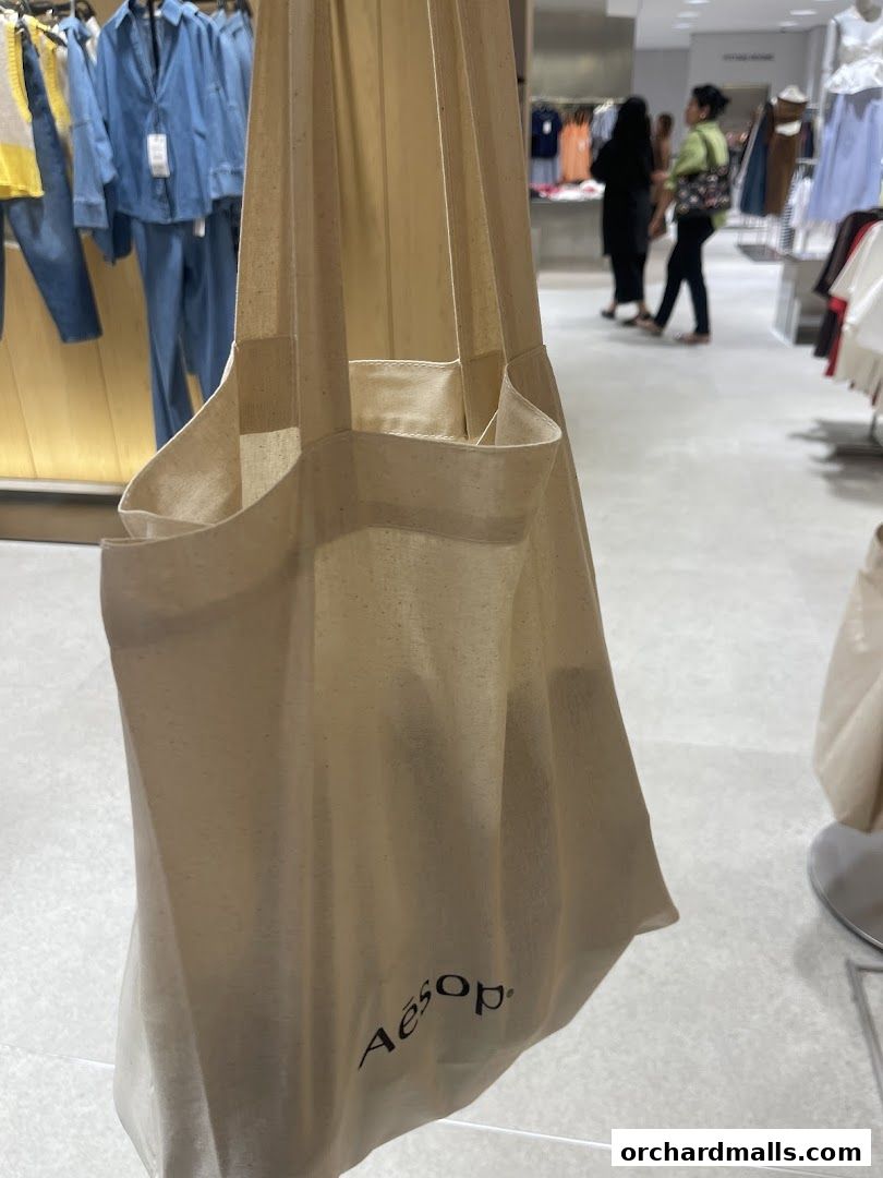 A close-up of a canvas tote bag with the Aesop logo, inside a store.
