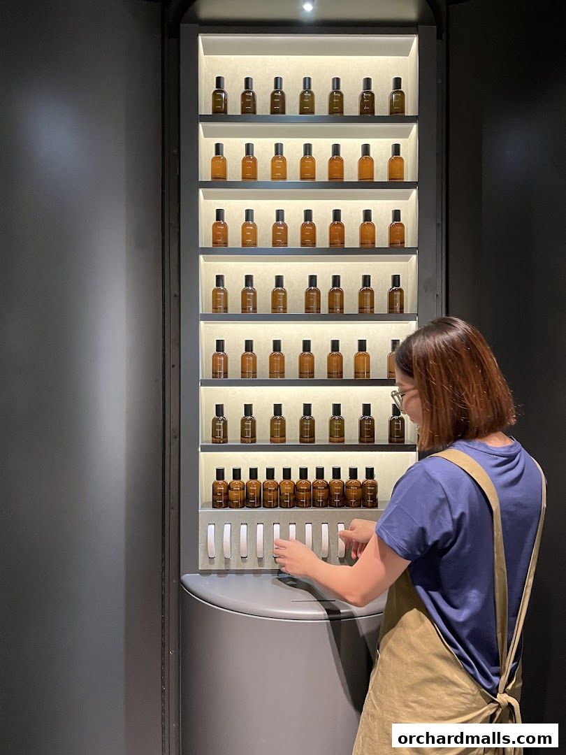 A woman interacts with a display of Aesop products, showcasing a curated selection of fragrances.