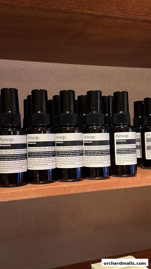 A row of Aesop Deodorant bottles displayed on a wooden shelf.