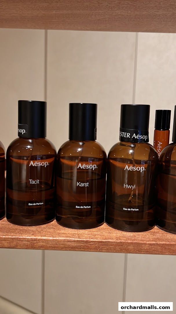 A close-up shot of Aesop perfume bottles displayed on a wooden shelf.